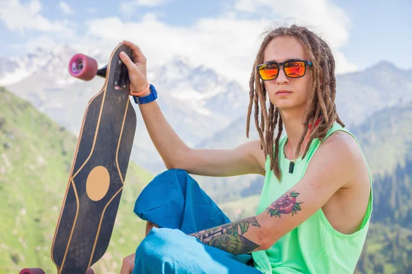 Hipster junger, gutaussehender Mann mit Longboard-Skateboard am Berg — Stockfoto