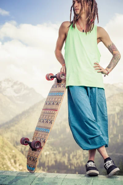 Hippie junger und gutaussehender Mann mit Longboard-Skateboard am Berg — Stockfoto