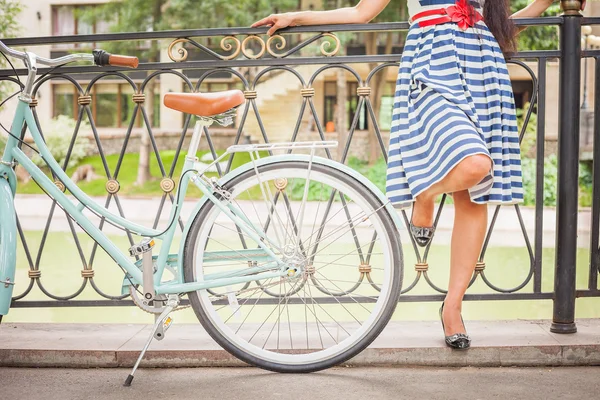 Young girl standing near fence near vintage bike at park — Stock Photo, Image