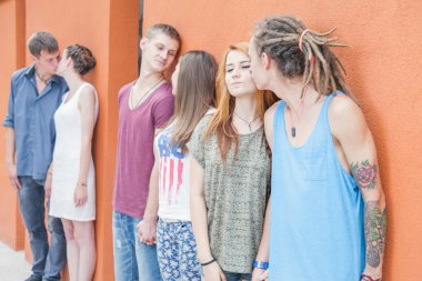 Medium group ofpeople kissing and standing near red wall background