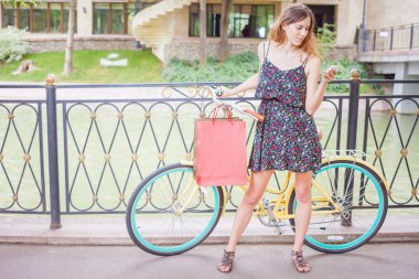 Pretty woman with bugs using mobile phone near vintage bicycle