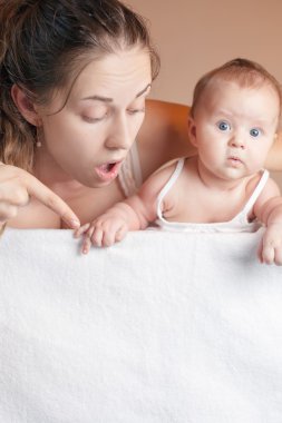 Mother with baby lying on white blanket and pointing down