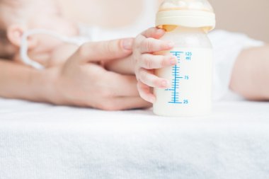 Baby holding a baby bottle with breast milk