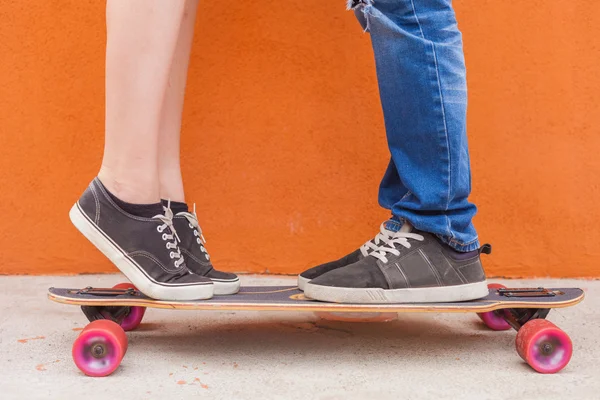 Primer plano besos pareja en el monopatín y fondo de la pared roja — Foto de Stock