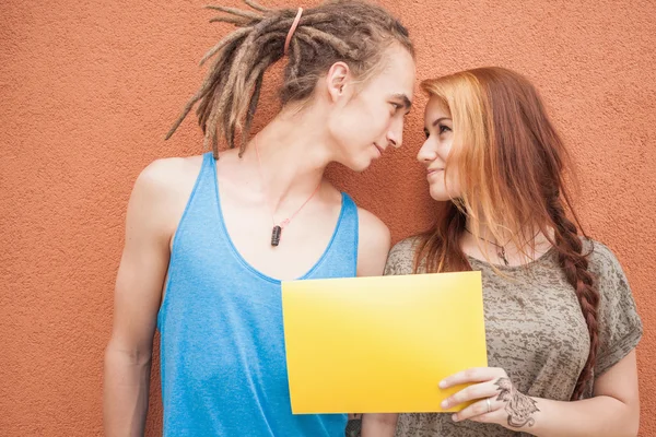 Happy teenagers couple looking and holding frame at red background — Zdjęcie stockowe