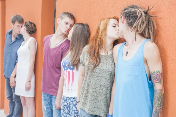 Grupo medio de personas besándose y de pie cerca de fondo rojo de la pared — Foto de Stock