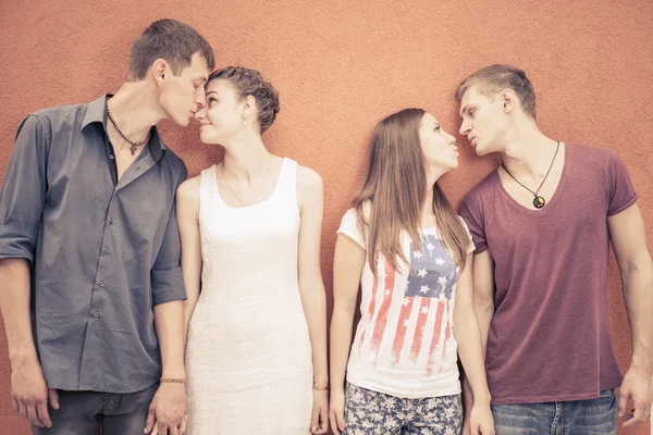 Μικρή ομάδα ανθρώπων φιλιά, στέκεται κοντά σε φόντο κόκκινο τοίχο — Φωτογραφία Αρχείου