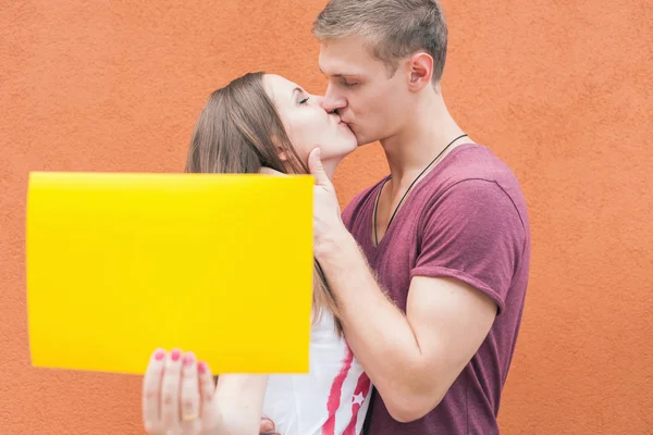 Young couple kissing and holding frame at background of wall — Stok fotoğraf