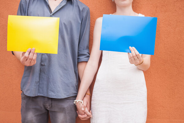 Closeup couple holding hands and holding frames at wall background