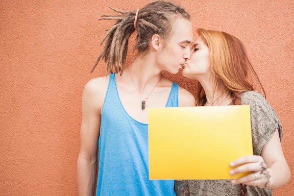 Fashion teenagers couple kissing and holding frame at red background — 图库照片