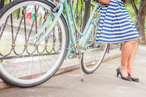 Young girl standing near fence near vintage bike at park — Stock Photo, Image