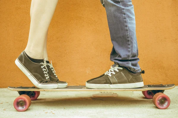 Primer plano besos pareja en el monopatín y fondo de la pared roja — Foto de Stock