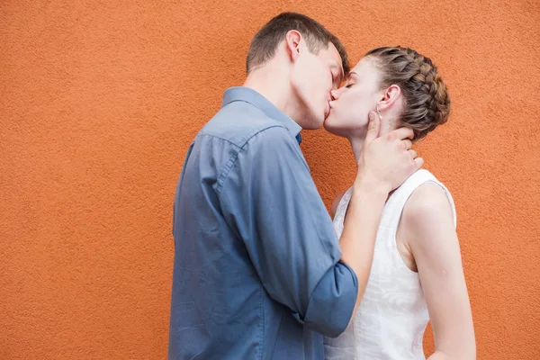 Kissing couple at red wall background — Stok fotoğraf