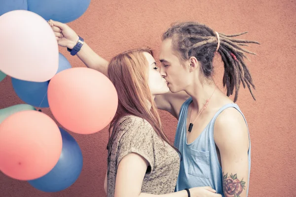 Happy and funny couple kissing at background of color balloons — Stok fotoğraf
