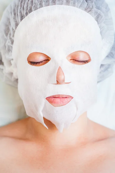 Woman relaxing in spa salon applying white face mask — Stock Photo, Image
