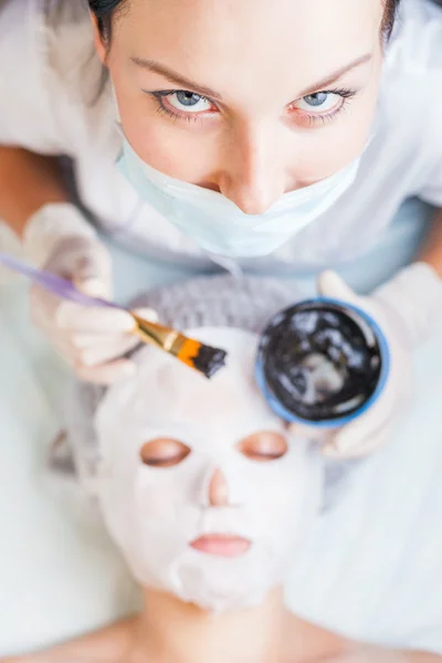 Mujer profesional, cosmetóloga en salón de spa aplicando mascarilla de barro — Foto de Stock