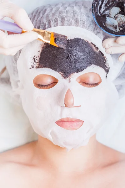 Cosmetologist in spa salon applying mud face mask using brush — Stock Photo, Image