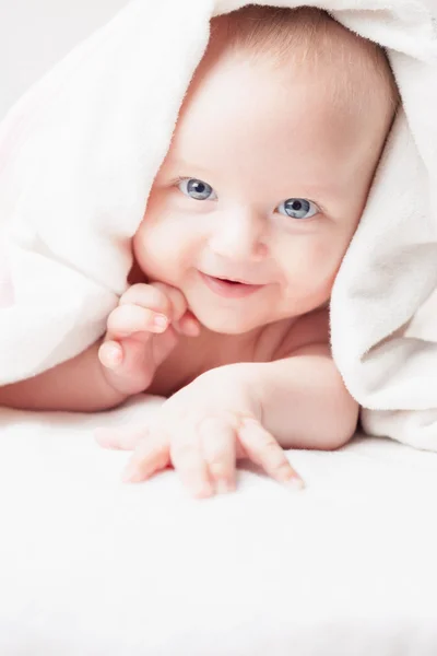 Happy baby after bathing, looks with white towels, funny smiles