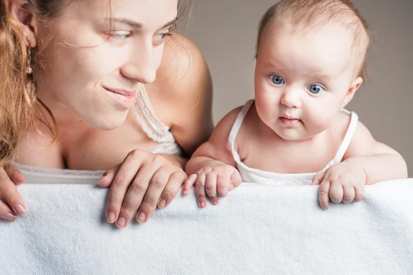 Ibu dengan bayi berbaring di atas selimut putih dan menunjuk ke bawah — Stok Foto