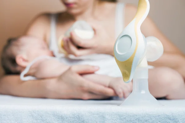 Manual breast pump and mother feeding a newborn baby — Stock Photo, Image