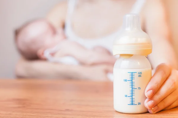 Mother holding a baby bottle with breast milk — Stok fotoğraf