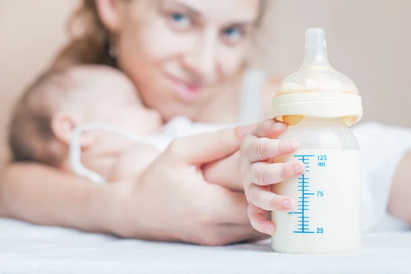 Bebê segurando uma mamadeira com leite materno — Fotografia de Stock