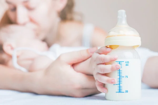 Bebé sosteniendo un biberón con leche materna — Foto de Stock