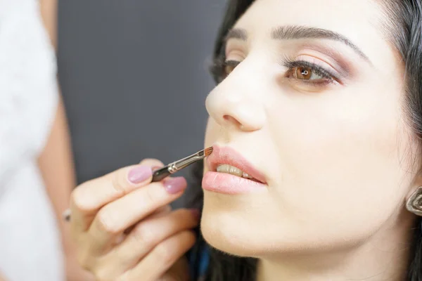 Spezialist für Schönheitssalon bekommt Lippenstift, Lipgloss, professionelles Make-up. — Stockfoto