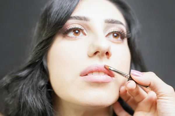 Spezialist für Schönheitssalon bekommt Lippenstift, Lipgloss, professionelles Make-up. — Stockfoto