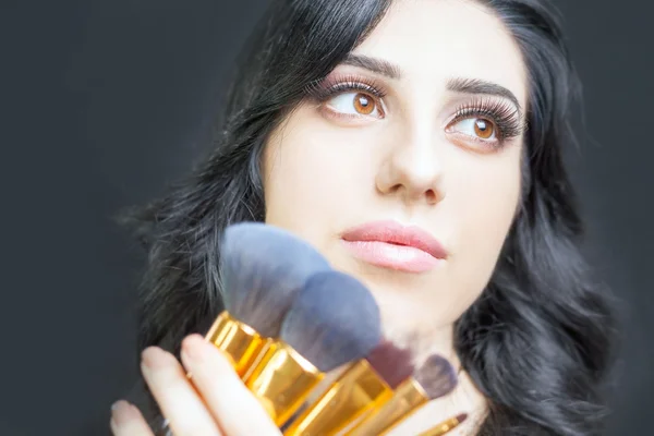 Beautiful woman at beauty salon with set of makeup brushes — Stock Photo, Image