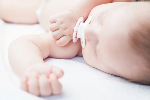 Newborn baby sweet sleeping on a white bed with pacifier — ストック写真