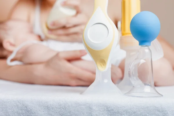 Manual breast pump and mother feeding a newborn baby — Stock Photo, Image