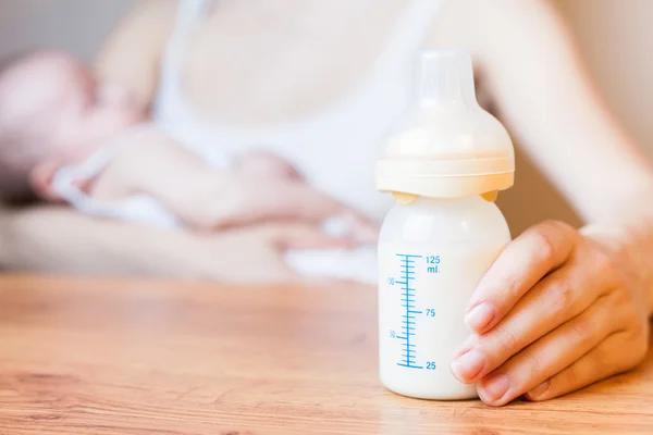 Mutter in der Hand eine Babyflasche mit Muttermilch mit Waage Stockbild