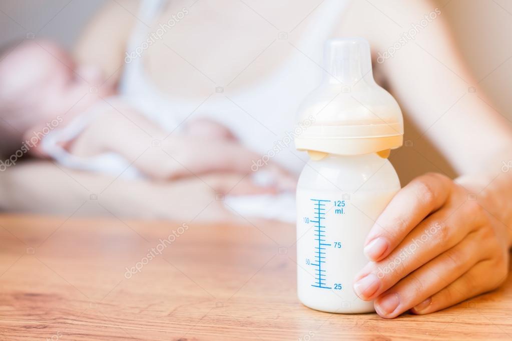 Mother holding a baby bottle with breast milk with scale