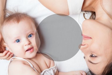 Happy mother with a baby lying on a white bed