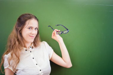 Pretty teacher or student holding glasses at classroom, university