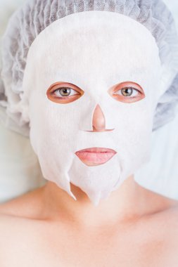 Kadın rahatlatıcı spa salonda beyaz yüz maskesi uygulama