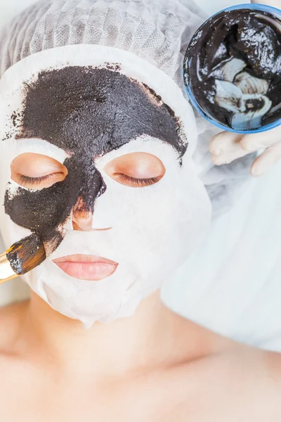 Cosmetologist in spa salon applying mud face mask using brush — Stock Photo, Image