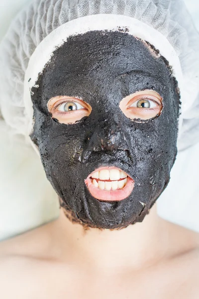 Creative woman in spa salon with black mud face mask — Stock Photo, Image