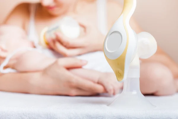 Manual breast pump and mother feeding a newborn baby — Stock Photo, Image