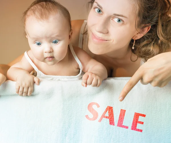 Sale concept with mom and baby lying on white blanket — Zdjęcie stockowe