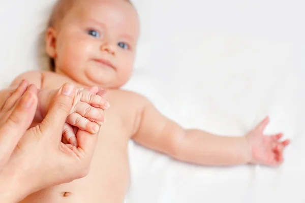 Mother makes baby massage with happy newborn at white bed — Stock Photo, Image