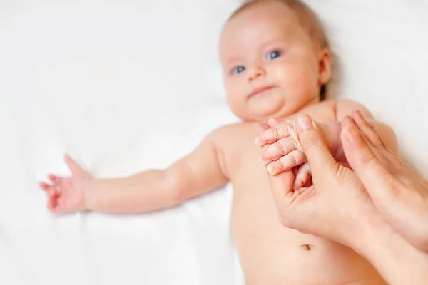 Ibu membuat pijat bayi dengan bayi yang baru lahir bahagia di tempat tidur putih — Stok Foto