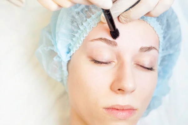 Профессиональная женщина в салоне красоты делает корректирующие брови — стоковое фото