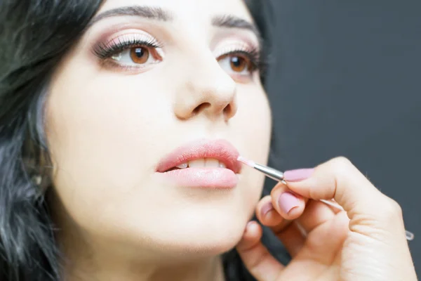 Closeup specialist in beauty salon gets lipstick, lip gloss, make-up. — Stock Photo, Image