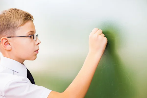 First grade schoolboy wrote on blackboard with chalk at classroom — Stock fotografie