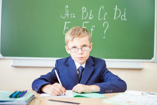 Schoolboy sits at a desk at school classroom — Stock Photo, Image