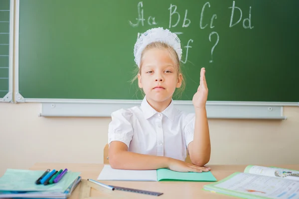 Skolflicka sitter vid skrivbord, skola klassrummet, på bakgrund av styrelsen — Stockfoto