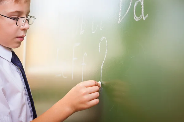 School boy writes English alphabet with chalk on blackboard — Stock Photo, Image