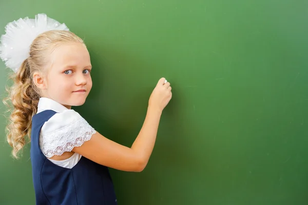 First grade schoolgirl wrote on blackboard with chalk at classroom — Stock fotografie